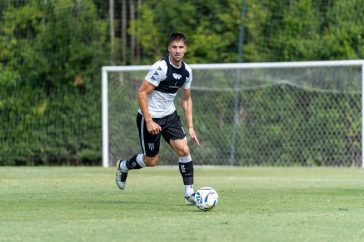 Soccer player dribbling the ball during practice outdoors on a sunny day.